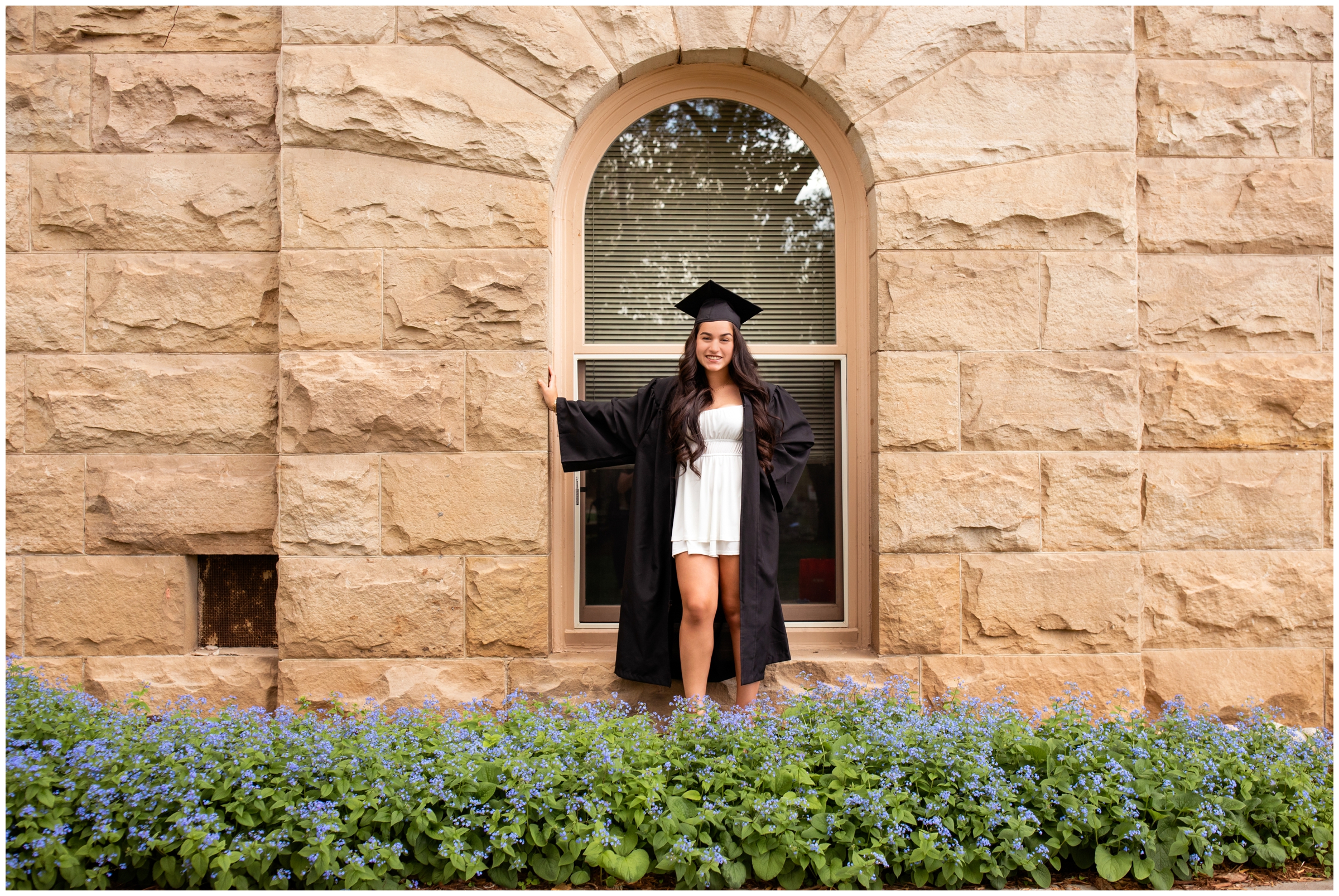 college graduate posing in front of arched window at the colorado school of mines college senior portraits 