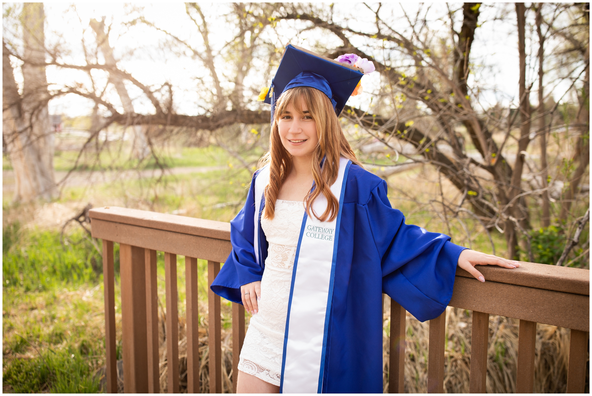 teen posing on wooden bridge at McKay Lake during cap and gown senior portraits in Westminster Colorado
