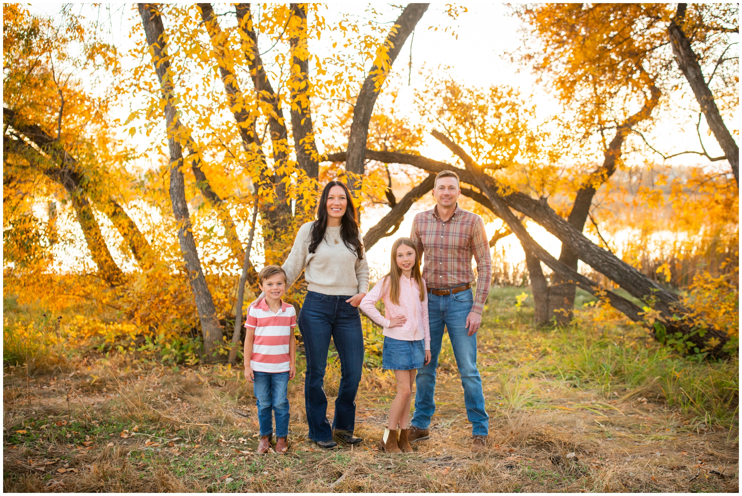 family posing in front of colorful fall foliage during photography mini sessions in Mead Colorado 