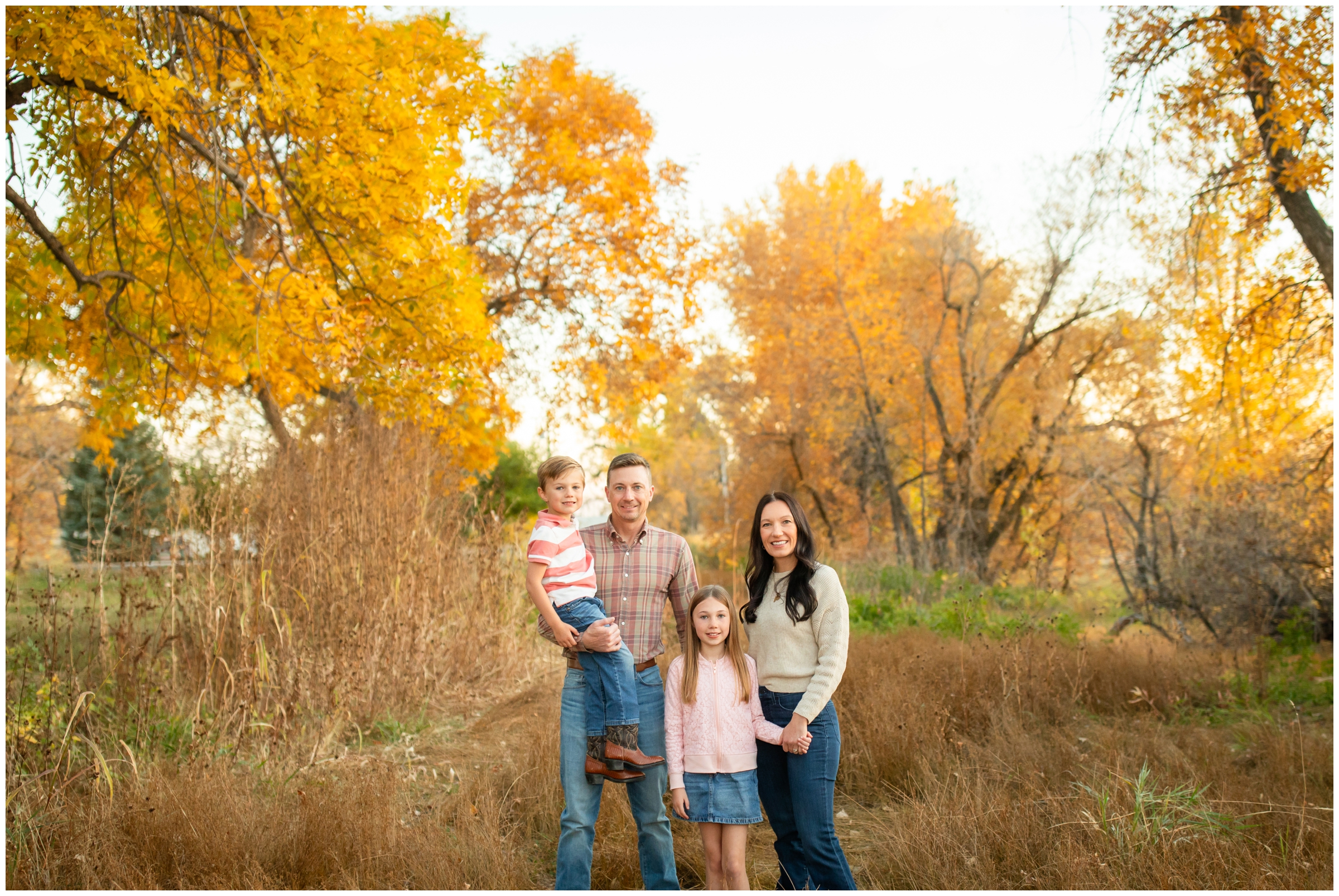 family posing in front of colorful fall foliage during Mead Colorado family photography session by Plum Pretty Photos